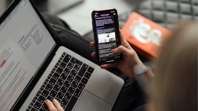 femme qui regarde son cellulaire et son ordinateur portable pour planifier ses publications sur son site WordPress